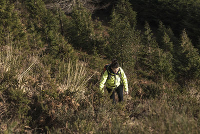 Mountaineer woman climbing a steep slope among the undergrowth