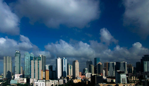 Low angle view of cityscape against cloudy sky