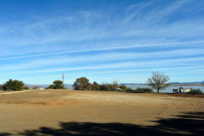 Trees on landscape against blue sky