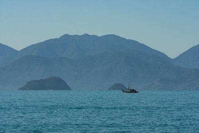 Sailboat in sea against mountains