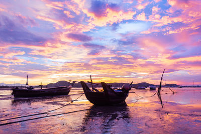 Boats moored on sea against sky during sunset