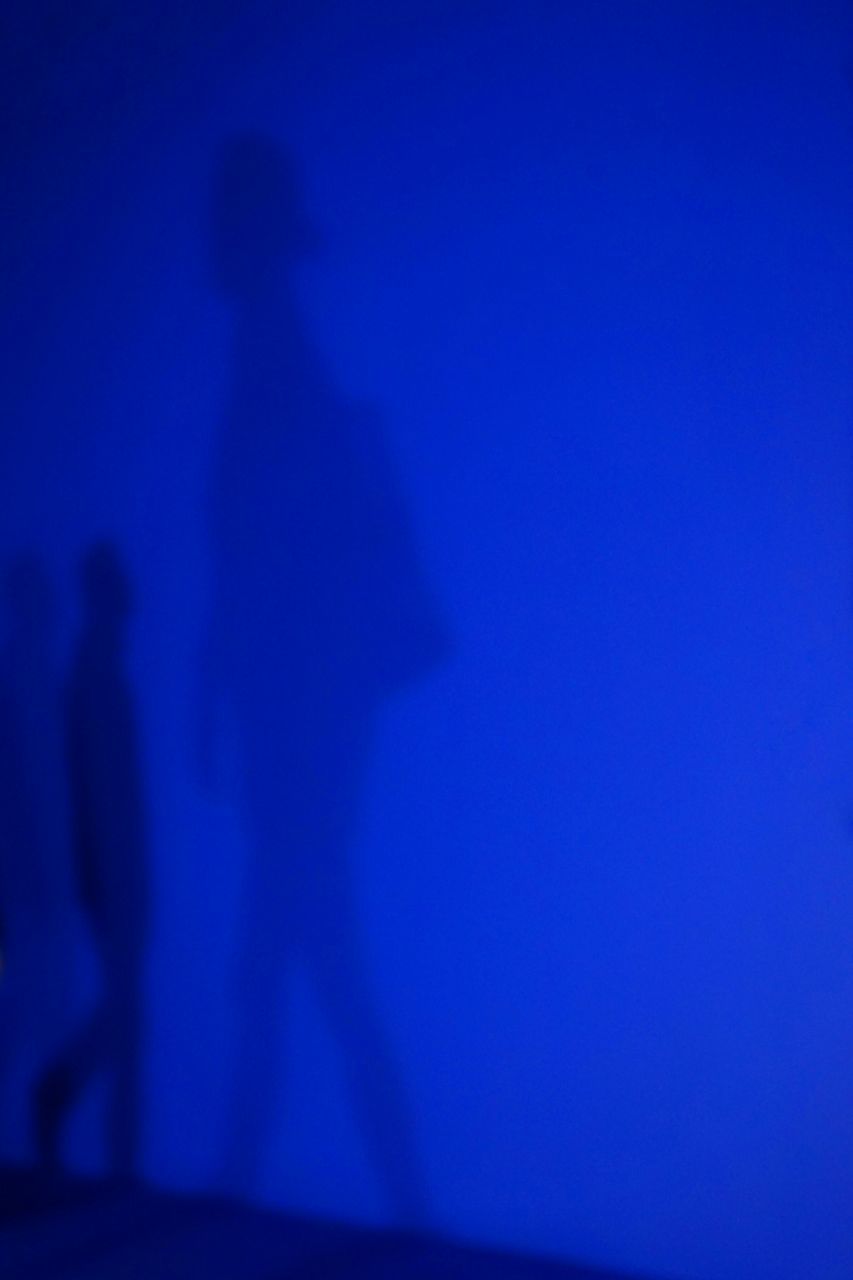 SHADOW OF MAN ON BLUE WALL