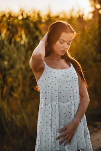 Young beautiful woman in white dress in corn field.