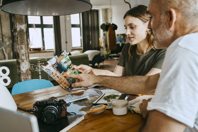 Male and female business colleagues discusing over photograph in studio