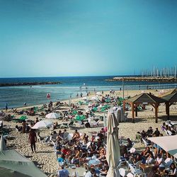 People at beach against clear blue sky