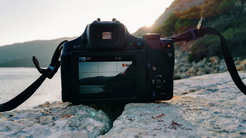 Close-up of camera photographing mountain against sky