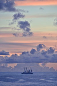 Sailboat sailing on sea against sky during sunset