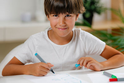 Boy writing letters on preschool screening test.