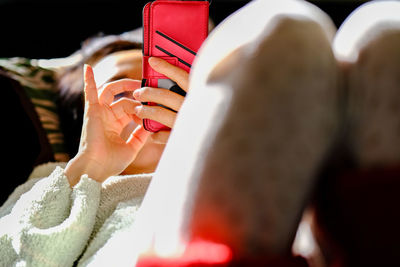 Woman using mobile phone while lying on sofa in pajamas in the morning light 