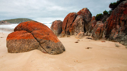 Rock formation on beach against sky