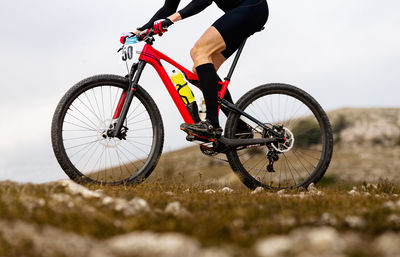 Low section of man riding bicycle on field