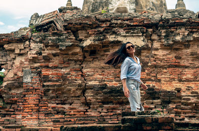 Full length of woman standing against brick wall