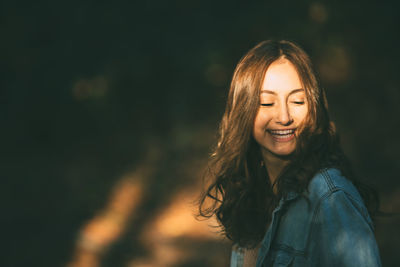 Young woman smiling against wall