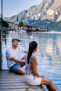 Young couple sitting on lake against mountains