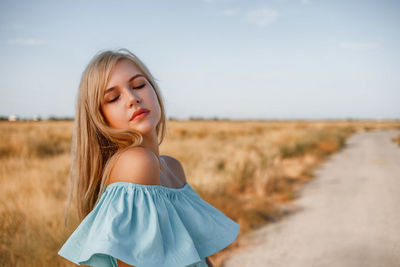 Side view of teenage girl with eyes closed wearing dress standing on land against sky