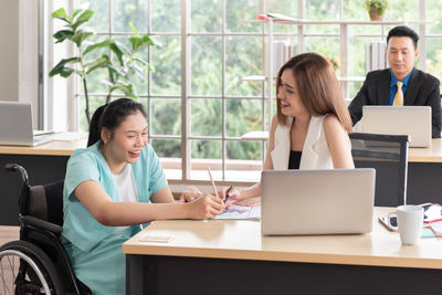 Smiling female colleagues discussing at desk in office