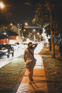 Full length of woman walking on street in city at night