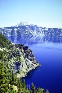 Scenic view of sea and mountains against clear blue sky