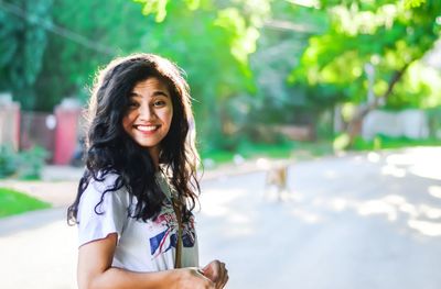 Portrait of smiling young woman against trees