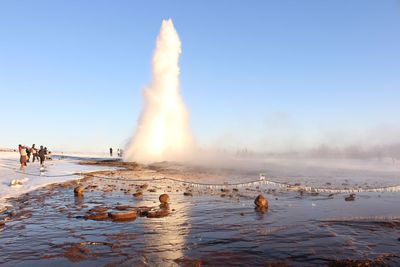 Geyser erupting against clear sky