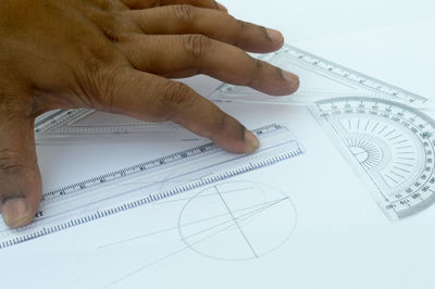 Close-up of hand holding paper over white background