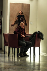 Portrait of couple sitting on chair at home