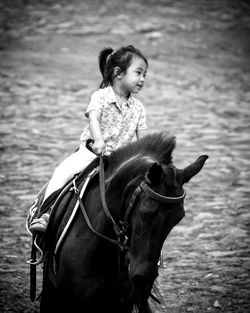 Girl riding horse on field