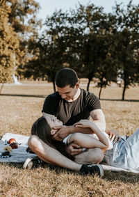A young couple looks tenderly into each other's eyes on a picnic in the park.
