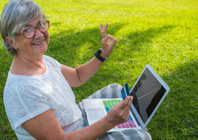 Rear view of woman using mobile phone in grass