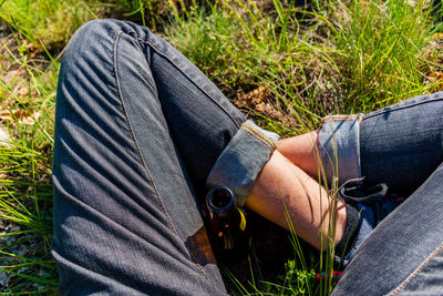 Low section of man with beer bottle sitting on grass