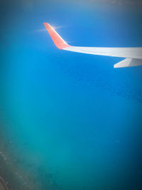 Airplane flying over sea against blue sky