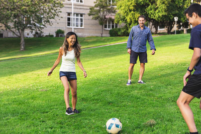 Happy family playing football on grass in lawn