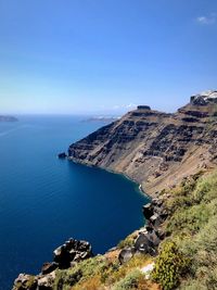 Scenic view of sea and rocks against blue sky