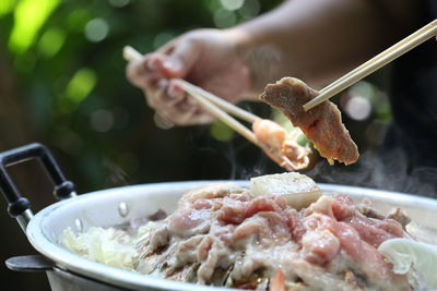 Cropped hand of person holding food with chopsticks