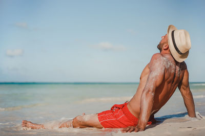 Low angle view of shirtless man at beach against sky