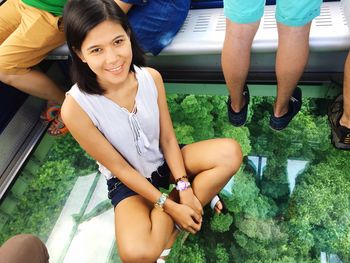 High angle portrait of young woman sitting on glass floor in overhead cable car