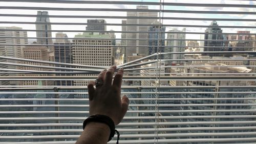 Close-up of hand holding cigarette against sky in city