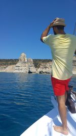 Rear view of woman standing by sea against clear sky