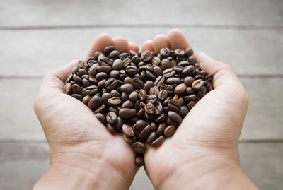 Close-up of hands holding roasted coffee beans