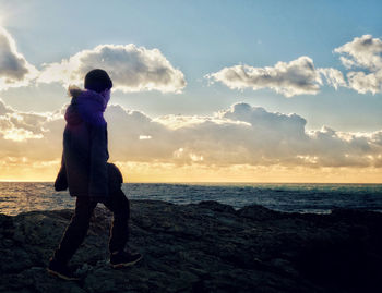 Man on beach against sky during sunset