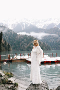 A tender sensual young woman bride in a fashionable wedding dress is standing in the rain in nature