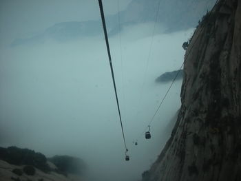 Low angle view of hanging by sea against sky