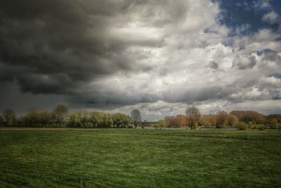 Scenic view of grassy field against cloudy sky