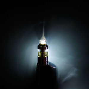 Close-up of illuminated bottle against black background