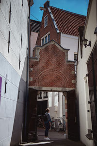People walking on alley amidst buildings in city