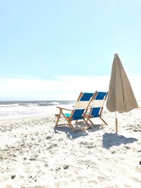 Deck chairs on beach against clear sky