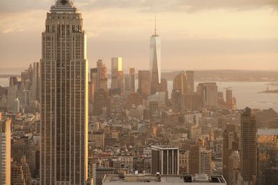 Empire state building and one world trade center in city during sunset