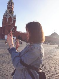 Woman standing in front of building against clear sky