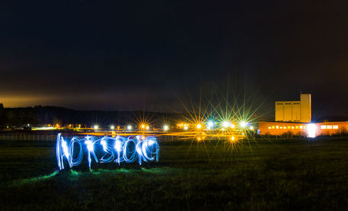 Illuminated field against sky at night