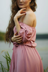 Shoulder of young woman standing near river landscape in twilight